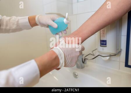 Nurse disinfects a patients hand at a sink Stock Photo