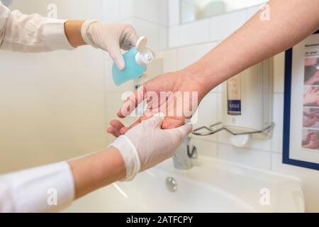 Nurse disinfects a patients hand at a sink Stock Photo