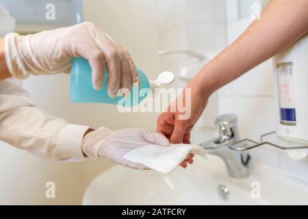 Nurse disinfects a patients hand at a sink Stock Photo