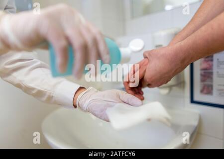 Nurse disinfects a patients hand at a sink Stock Photo