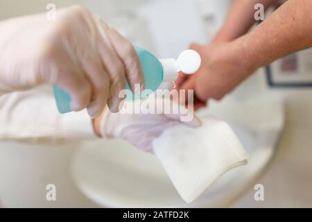 Nurse disinfects a patients hand at a sink Stock Photo