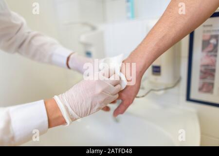 Nurse disinfects a patients hand at a sink Stock Photo