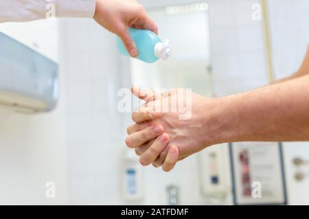 Nurse disinfects a patients hand at a sink Stock Photo