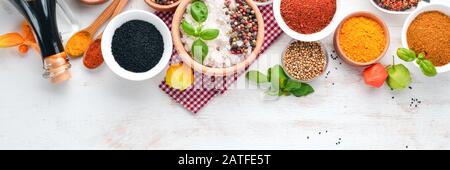 A set of Spices and herbs on a white wooden table. Basil, pepper, saffron, spices. Indian traditional cuisine. Top view. Free copy space. Stock Photo