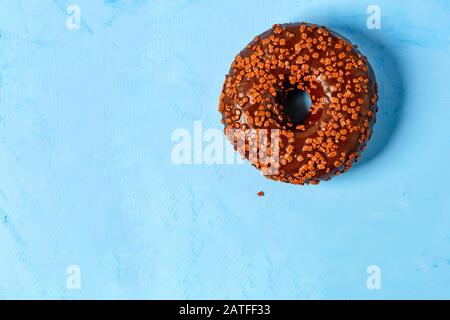 Delicious chocolate donut on a blue concrete surface. Stock Photo
