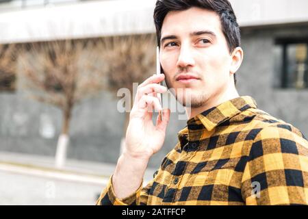 close up portrait of a serious man with focused view speaking on the phone and looking away Stock Photo