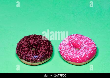 Delicious chocolate and cream donuts on a light green rough surface. Stock Photo