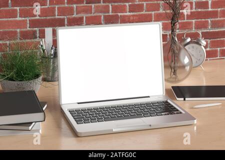 Workspace with blank laptop monitor white screen mock up on the wooden desk near red brick wall Stock Photo