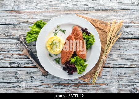 Cutlets of meat with mashed potatoes on a plate. On the old wooden background. Free space for text. Top view. Stock Photo
