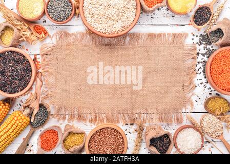 Set of Groats and Grains. Buckwheat, lentils, rice, millet, barley, corn, black rice. On a white wooden background. Top view. Copy space. Stock Photo