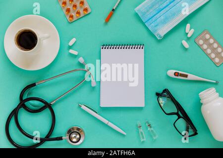 Doctor's desk top view. Stethoscope, pills, glasses and notebook on a colored background Stock Photo