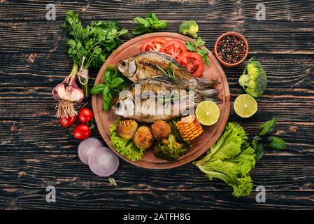 Baked fish with spices and vegetables. Carp On a wooden background. Top view. Copy space. Stock Photo