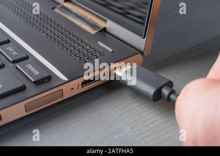 Closeup of USB Type C grey cable being connected to the laptop computer. Stock Photo