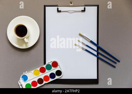 Workplace for creative work. Flat lay, gray background with notebook, paints and brushes. Stock Photo