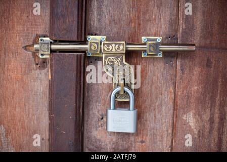 A close look at a classic, rusty and vintage metal padlock securing the entrance of an old house Stock Photo