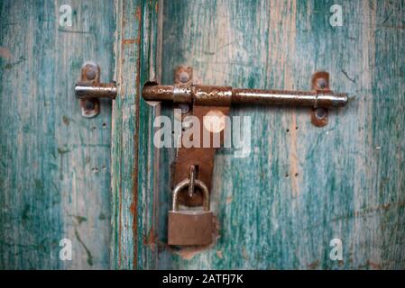 A close up shot of a brown and rusty iron padlock securing the safety of an aged gate Stock Photo