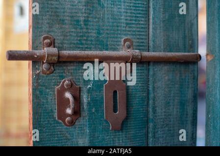 A close up photo of a brown vintage and rusty iron latch in the old gate of a house Stock Photo