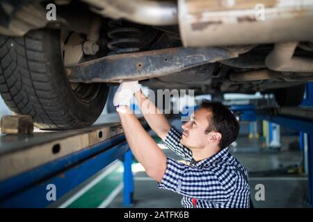 Portrait of a mechanic repairing a lifted car Stock Photo