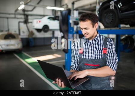 Mechanic using computer diagnostics while repairing car Stock Photo