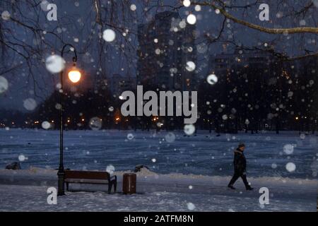 A man walking in a park during a heavy snowfall in an evening on a outskirts of the Moscow city, Russia Stock Photo
