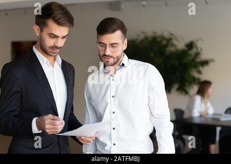 Focused colleagues discussing new common project standing in office Stock Photo