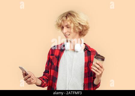 Young man using smartphone and holding paper cup in hand Stock Photo