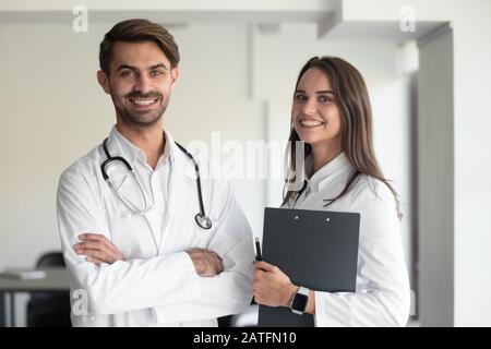 Happy female and male doctors wearing white coats posing indoors Stock Photo