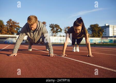 Young couple doing pushups in the stadium Stock Photo