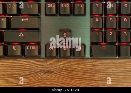 part of the black keyboard with red backlight near the arrow keys close-up Stock Photo