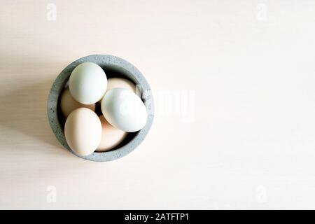 Natural organic Easter eggs and feathers in ceramic bowl on white background. Natural healthy food and organic farming, easter and spring concept. Stock Photo