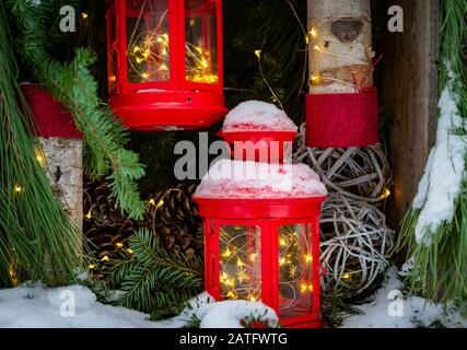 Christmas scene with lanterns, pine cones, snow, and green branches Stock Photo