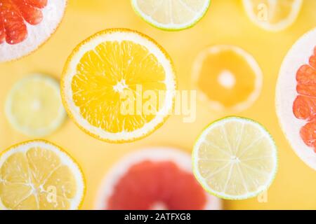 Pattern of different citrus fruit levitating above yellow background. Slices of orange, lemon, lime and grapefruit Stock Photo