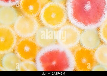 Blurry pattern of different citrus fruits on yellow background. Orange, lemon, lime and grapefruit slices. Out of focus, water drops texture Stock Photo