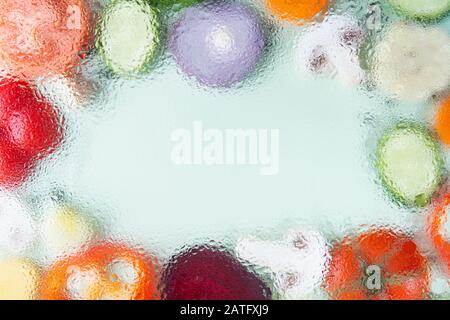 Assorted sliced vegetables on green background arranged in a frame with copy space in the middle. Out of focus image, water drops texture Stock Photo