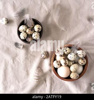White and brown Easter eggs, quail eggs and feathers on natural linen background. Easter background. Easter and healthy organic food concept. Stock Photo