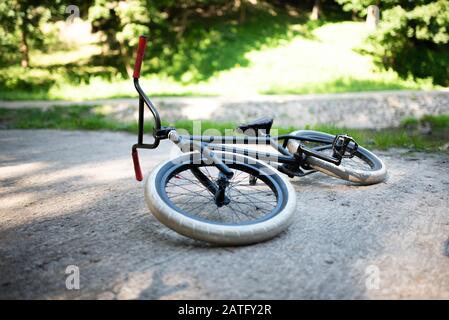 BMX bike lying on the pavement in the park. Stock Photo
