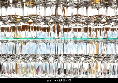 Wall of many empty transparent wine glasses on glass shelf at bar cafe or restaurant against backlit window. Abstract alcoholic beverages pub Stock Photo