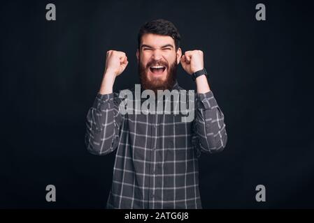 I am lucky. Bearded man is making the winner gesture. Stock Photo