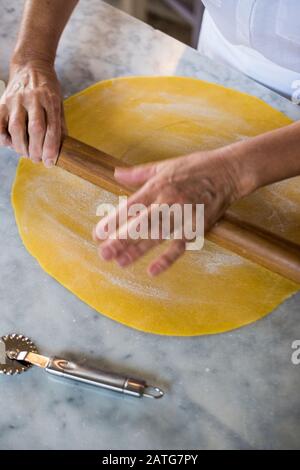 Italian woman hand rolling homemade Tortellini pasta dough Stock Photo
