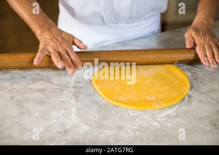 Italian woman rolling out homemade pasta dough Stock Photo