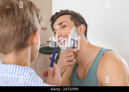Father and his little son shaving in bathroom Stock Photo