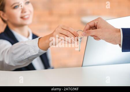 Female receptionist handing room key to man in hotel Stock Photo