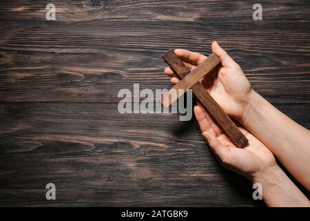 Female hands with christian cross on wooden background Stock Photo