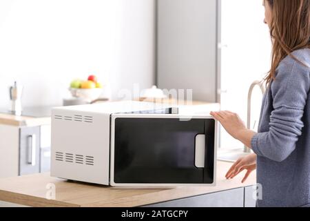 Woman opening modern microwave oven in kitchen Stock Photo
