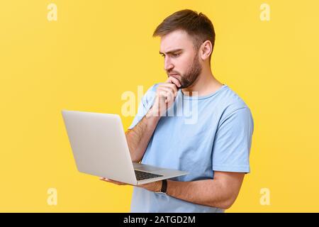 Thoughtful programmer with laptop on color background Stock Photo