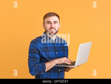 Male programmer with laptop on color background Stock Photo