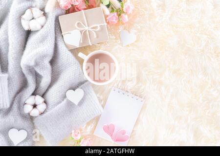 Pink paper hearts with gift box and roses, coffee cup on , beige sweater on cream colour knitted blanket and fluffy background. Love and Valentine's d Stock Photo