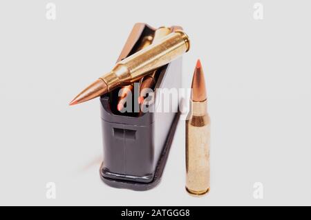 A loaded rifle magazine with two bullets not loaded into it on a white background Stock Photo