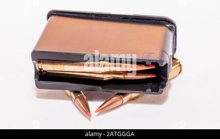 A loaded rifle magazine with two bullets not loaded into it on a white background Stock Photo