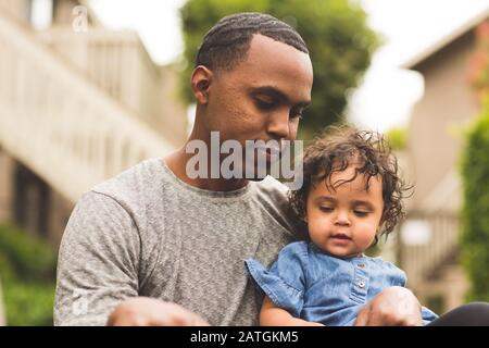 Father holding his little girl. Mixed race family.